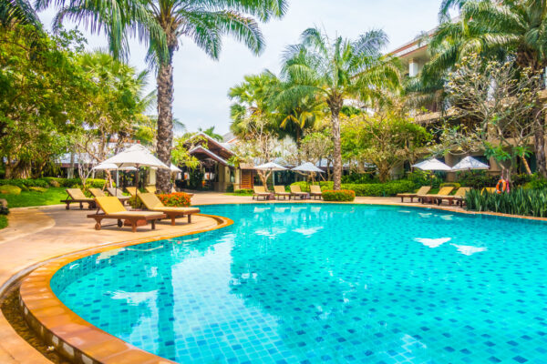 Beautiful luxury swimming pool with palm tree and sea background in hotel pool resort - Boost up color Processing